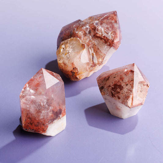 Three red phantom quartz crystal freeforms on a purple background