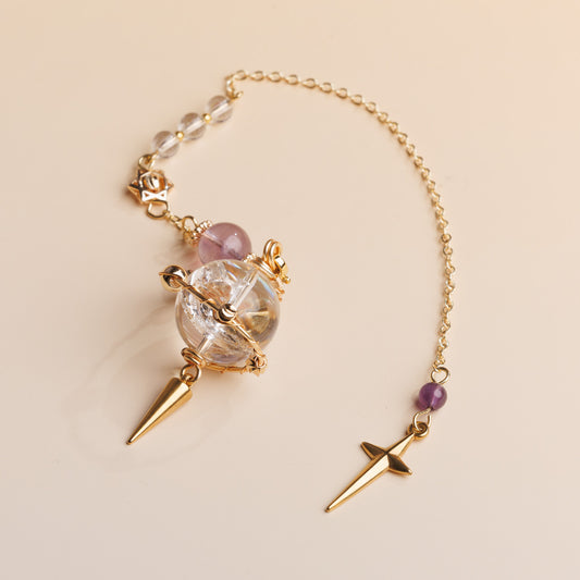 Pendulum with crystal and gold accents on a beige background