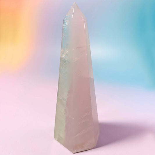 Yttrium Lavender Fluorite crystal obelisk tower on a rainbow gradient background.
